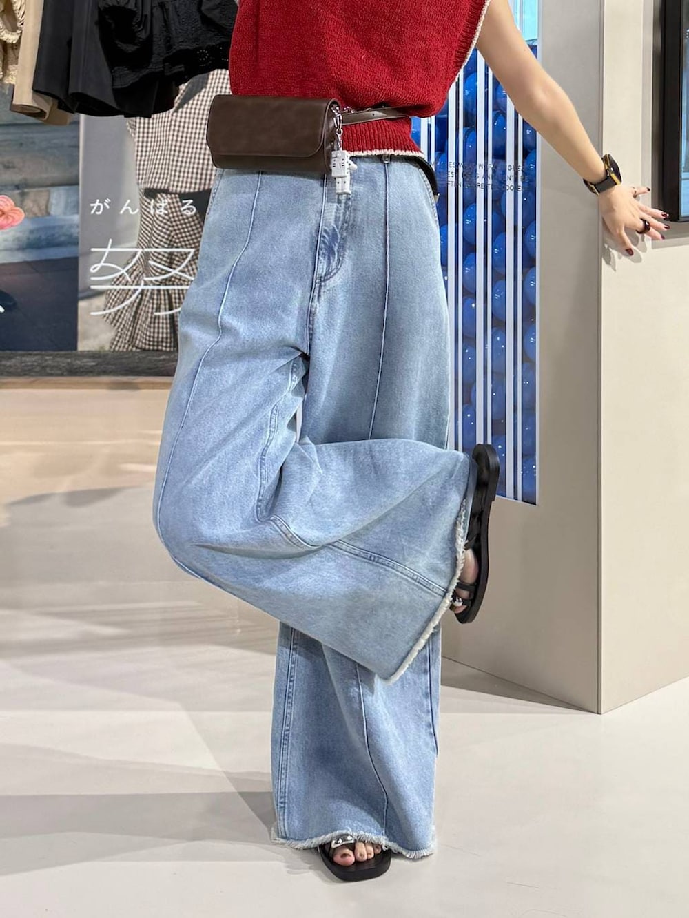 ブルー系のデニムパンツ、ブラック系のサンダル、レッド系のベストを着用したレディースの春コーディネートの5枚目の写真