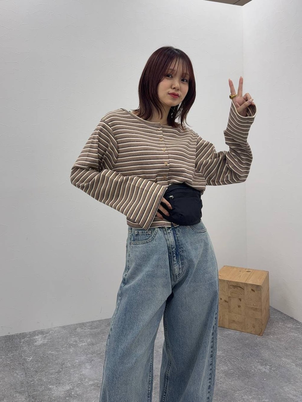 ブルー系のデニムパンツ、ブラック系のボディバッグ/ウエストポーチ、ベージュ系のカーディガン/ボレロを着用したレディースの冬コーディネートの2枚目の写真