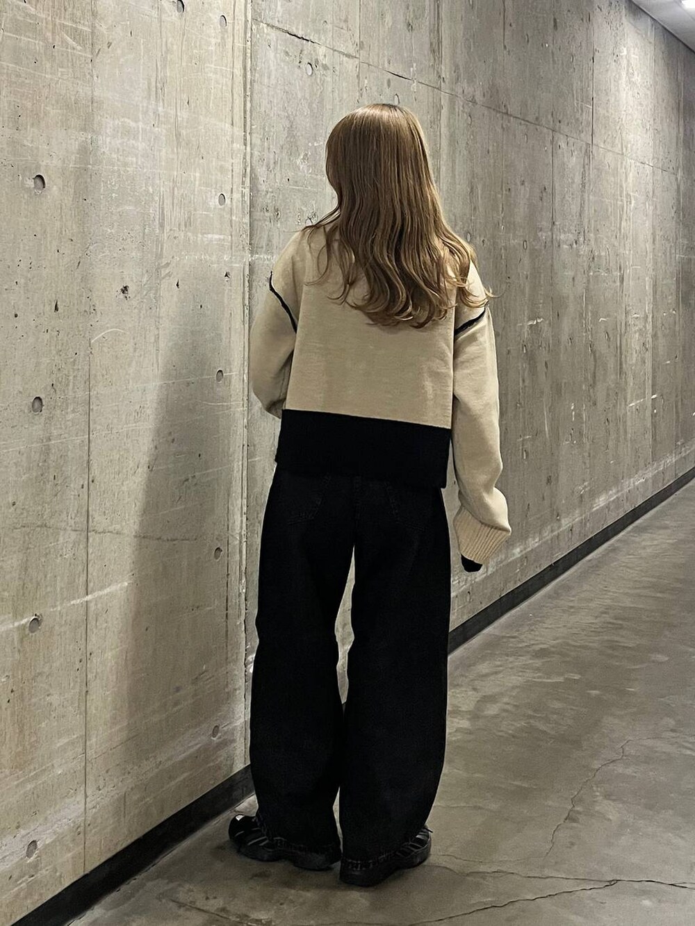 ベージュ系のニット/セーター、ブラック系のデニムパンツを着用したレディースの秋コーディネートの2枚目の写真
