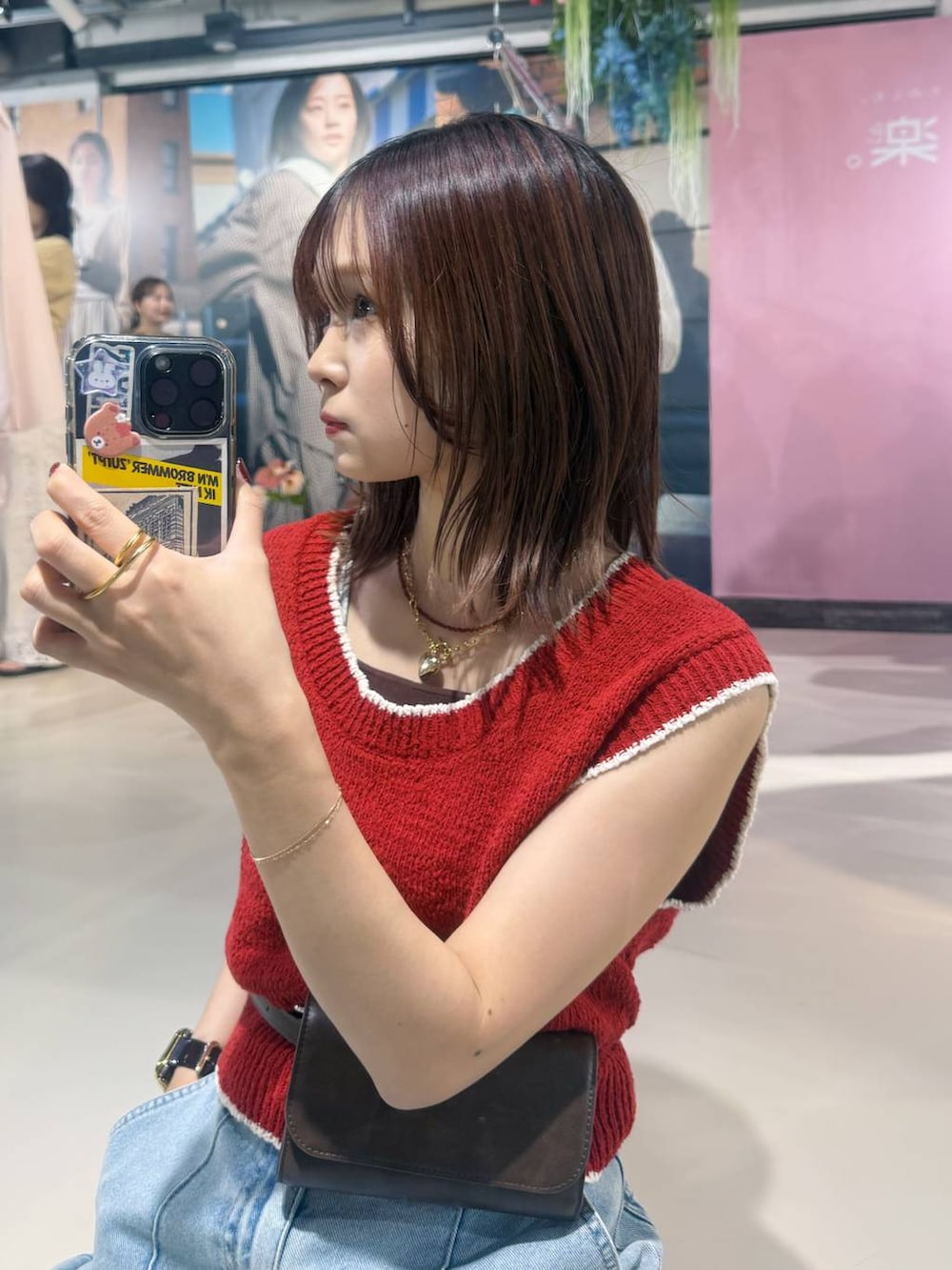 ブルー系のデニムパンツ、ブラック系のサンダル、レッド系のベストを着用したレディースの春コーディネートの8枚目の写真