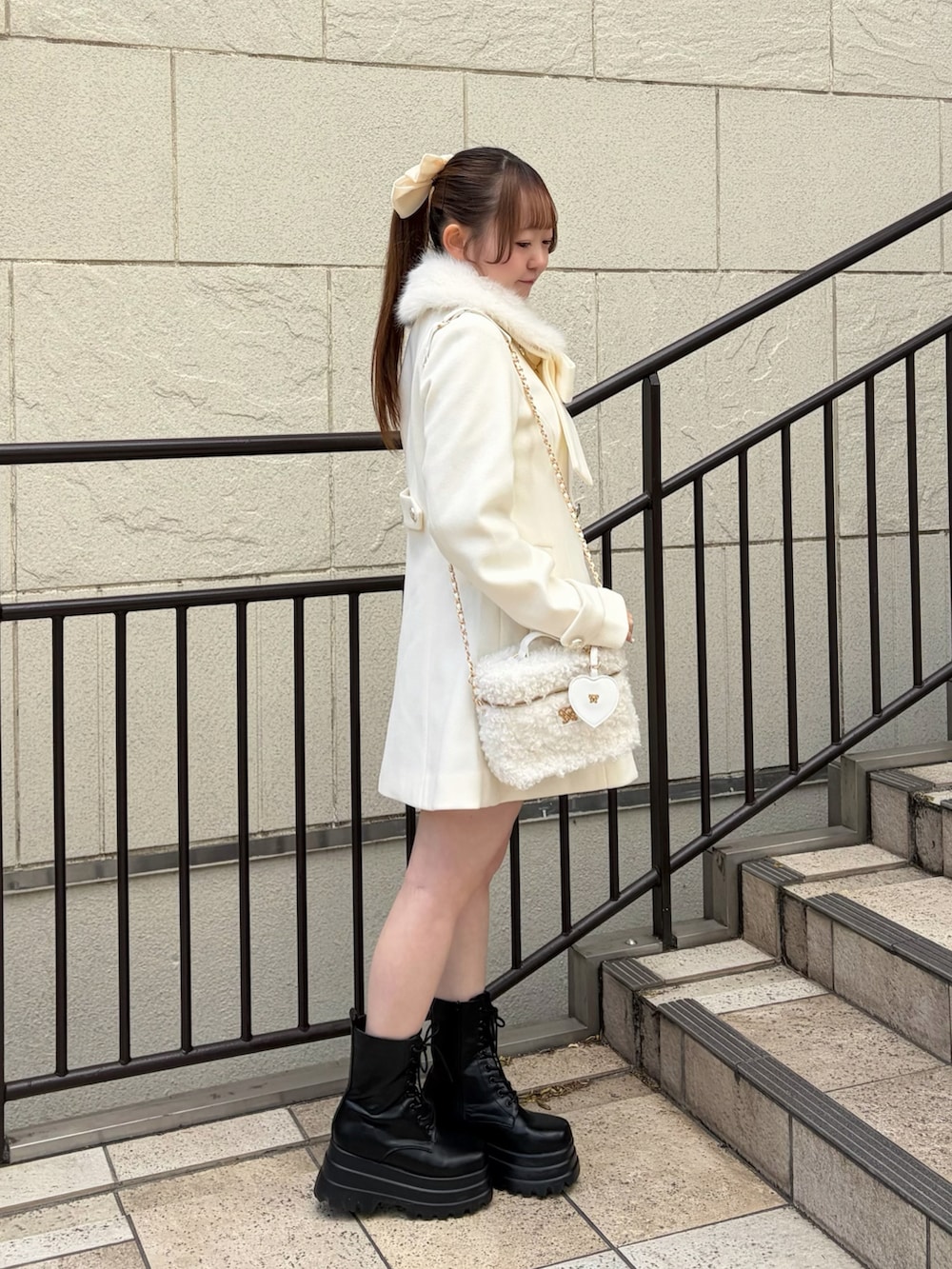 ホワイト系のステンカラーコート、ホワイト系のショルダーバッグ、ブラック系のブーツを着用したレディースの冬コーディネートの2枚目の写真