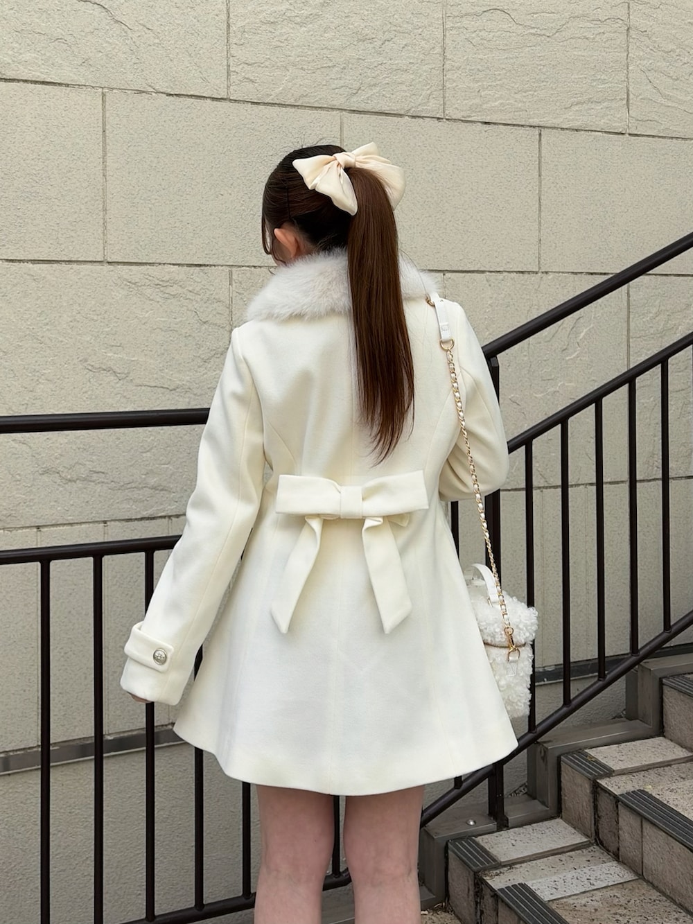 ホワイト系のステンカラーコート、ホワイト系のショルダーバッグ、ブラック系のブーツを着用したレディースの冬コーディネートの5枚目の写真