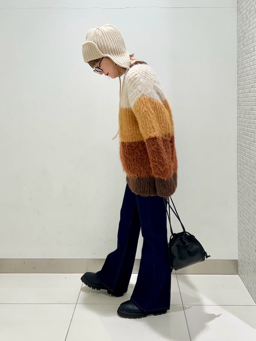 ブルー系のデニムパンツ、ブラック系のショルダーバッグ、ブラック系のブーツを着用したレディースの冬コーディネートの3枚目の写真