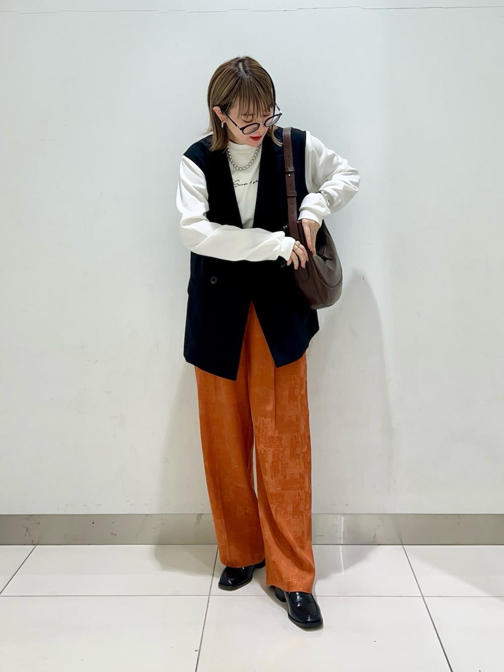 ブラウン系のショルダーバッグ、ブラック系のその他アウター、オレンジ系のその他パンツを着用したレディースの春コーディネートの6枚目の写真