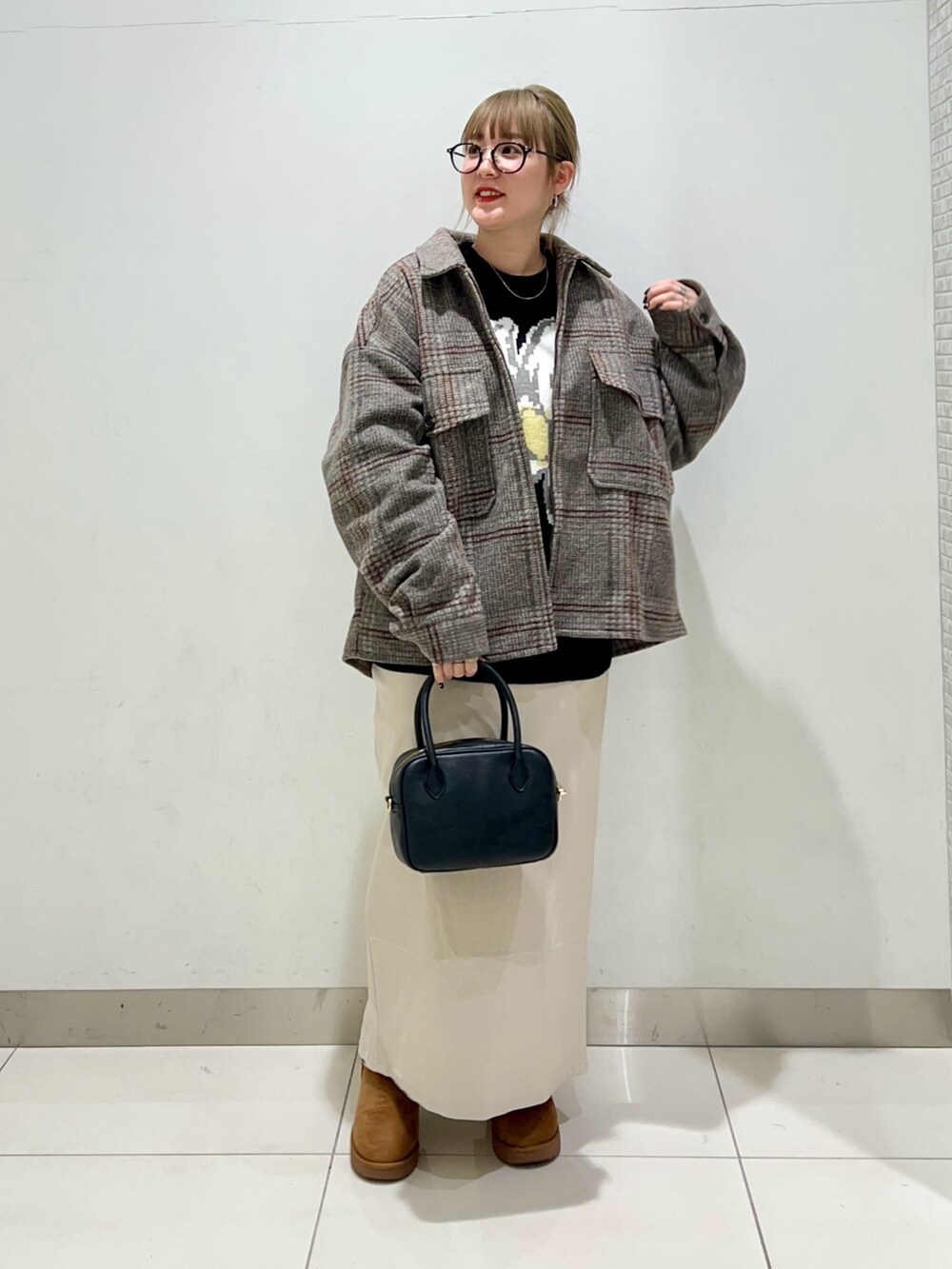 ブラック系のボストンバッグ、ベージュ系のスカート、ブラック系のニット/セーターを着用したレディースの冬コーディネートの2枚目の写真