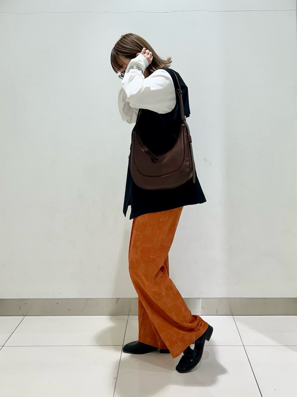 ブラウン系のショルダーバッグ、ブラック系のその他アウター、オレンジ系のその他パンツを着用したレディースの春コーディネートの3枚目の写真