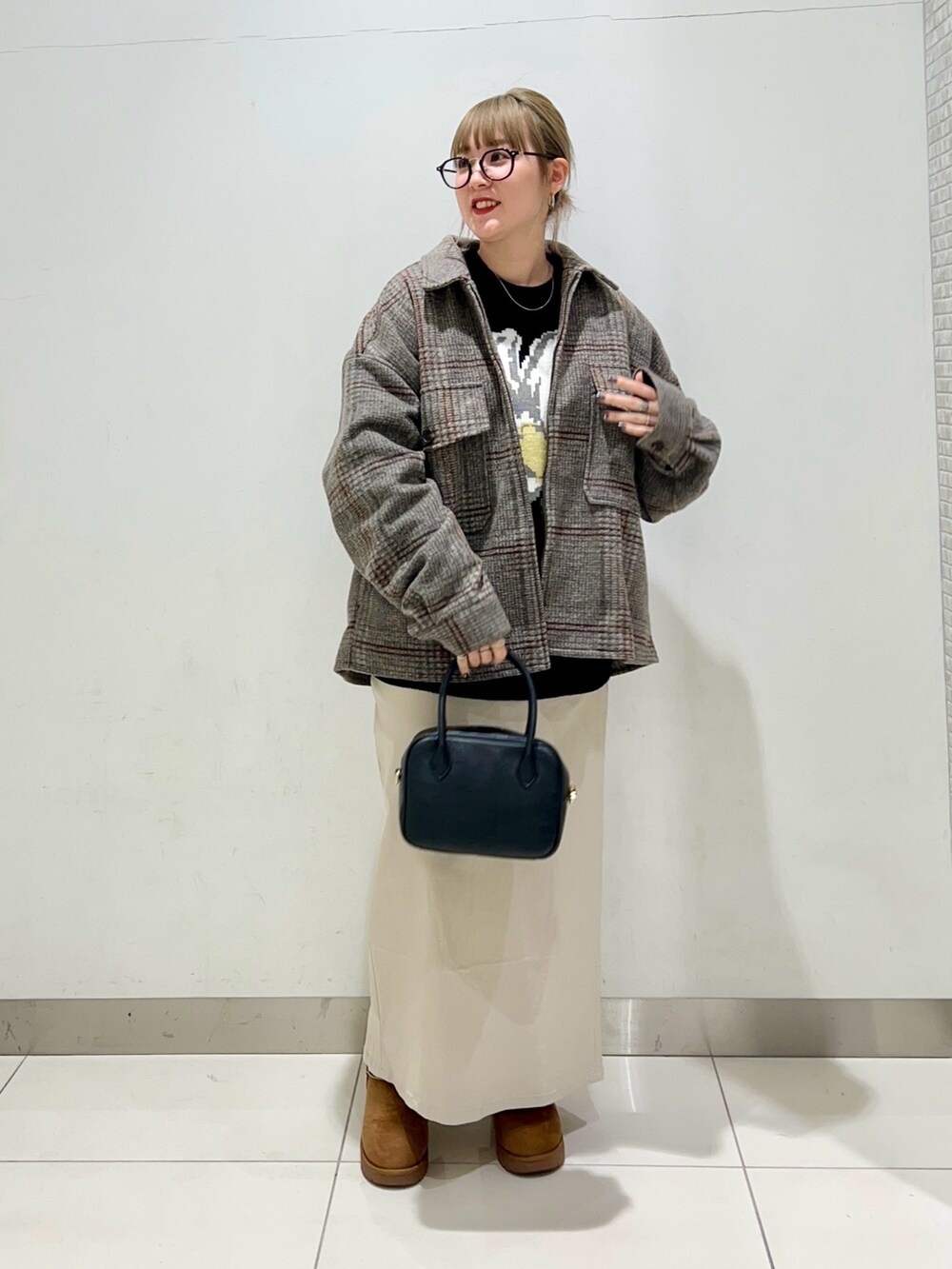 ブラック系のボストンバッグ、ベージュ系のスカート、ブラック系のニット/セーターを着用したレディースの冬コーディネートの6枚目の写真
