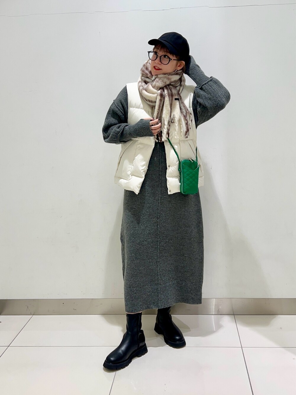 ブラック系のブーツ、グリーン系のショルダーバッグ、ホワイト系のダウンベストを着用したレディースの秋コーディネートの7枚目の写真