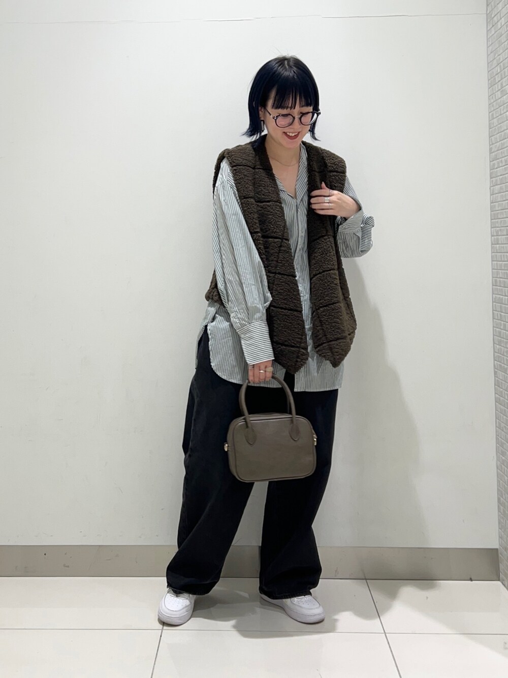 ブラック系のデニムパンツ、ブラウン系のボストンバッグ、グリーン系のシャツ/ブラウスを着用したレディースの秋コーディネートの2枚目の写真