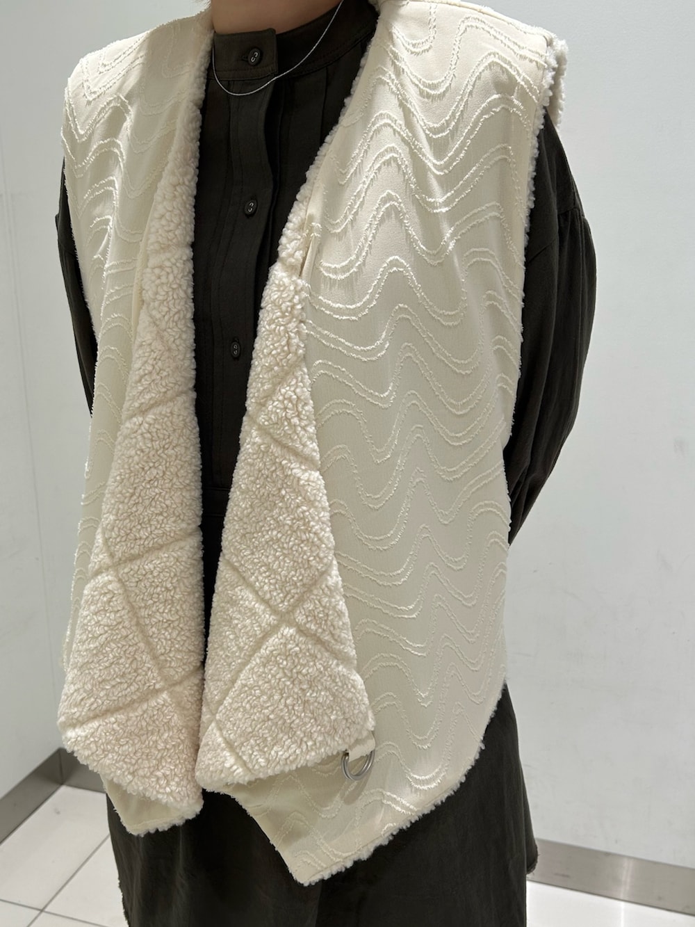 ホワイト系のベスト、グリーン系のワンピース、グレー系のその他パンツを着用したレディースの秋コーディネートの9枚目の写真