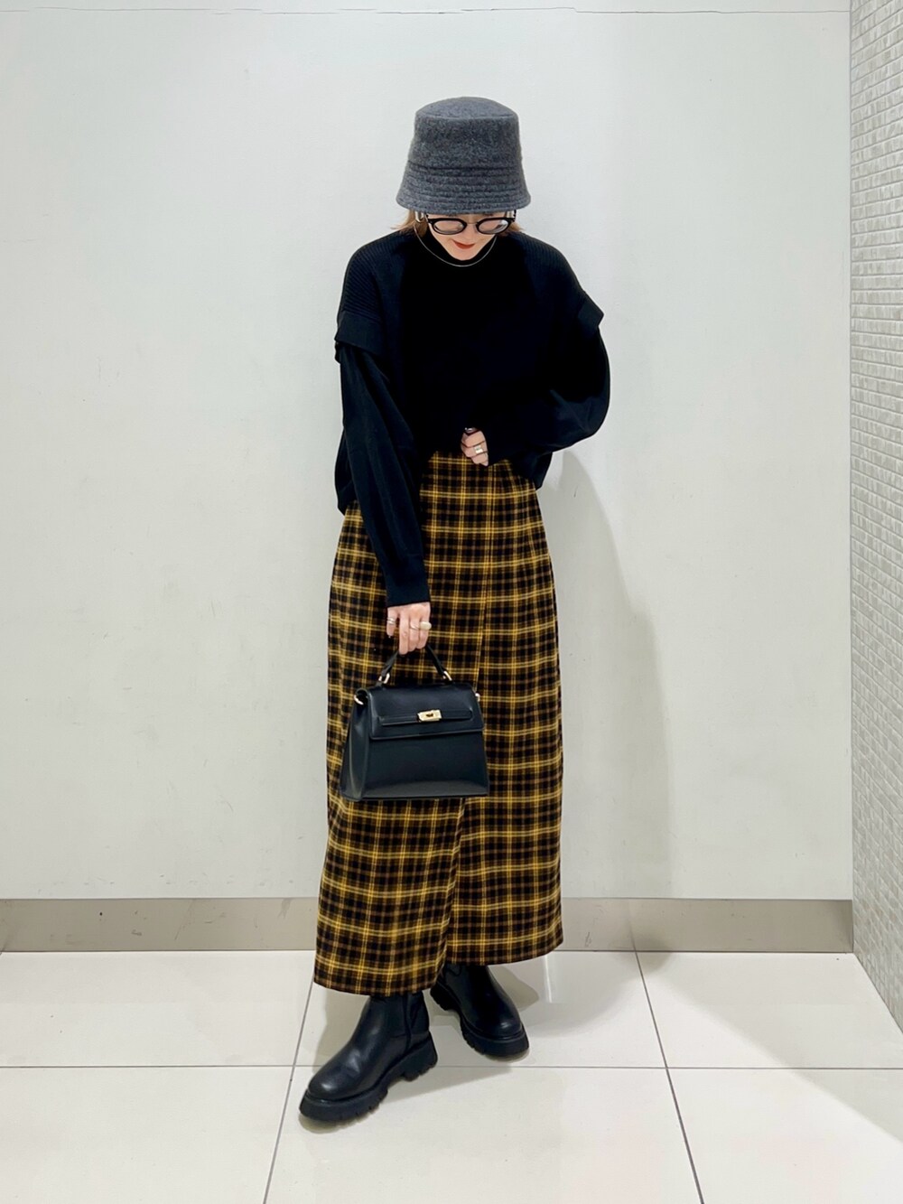 ホワイト系のジャケット/アウター、ブラック系のニット/セーター、イエロー系のスカートを着用したレディースの冬コーディネートの8枚目の写真