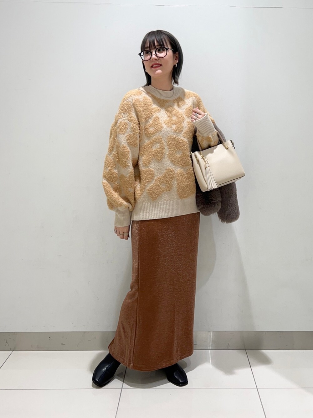 ブラック系のブーツ、ホワイト系のトートバッグ、ブラウン系のスカートを着用したレディースの秋コーディネートの8枚目の写真