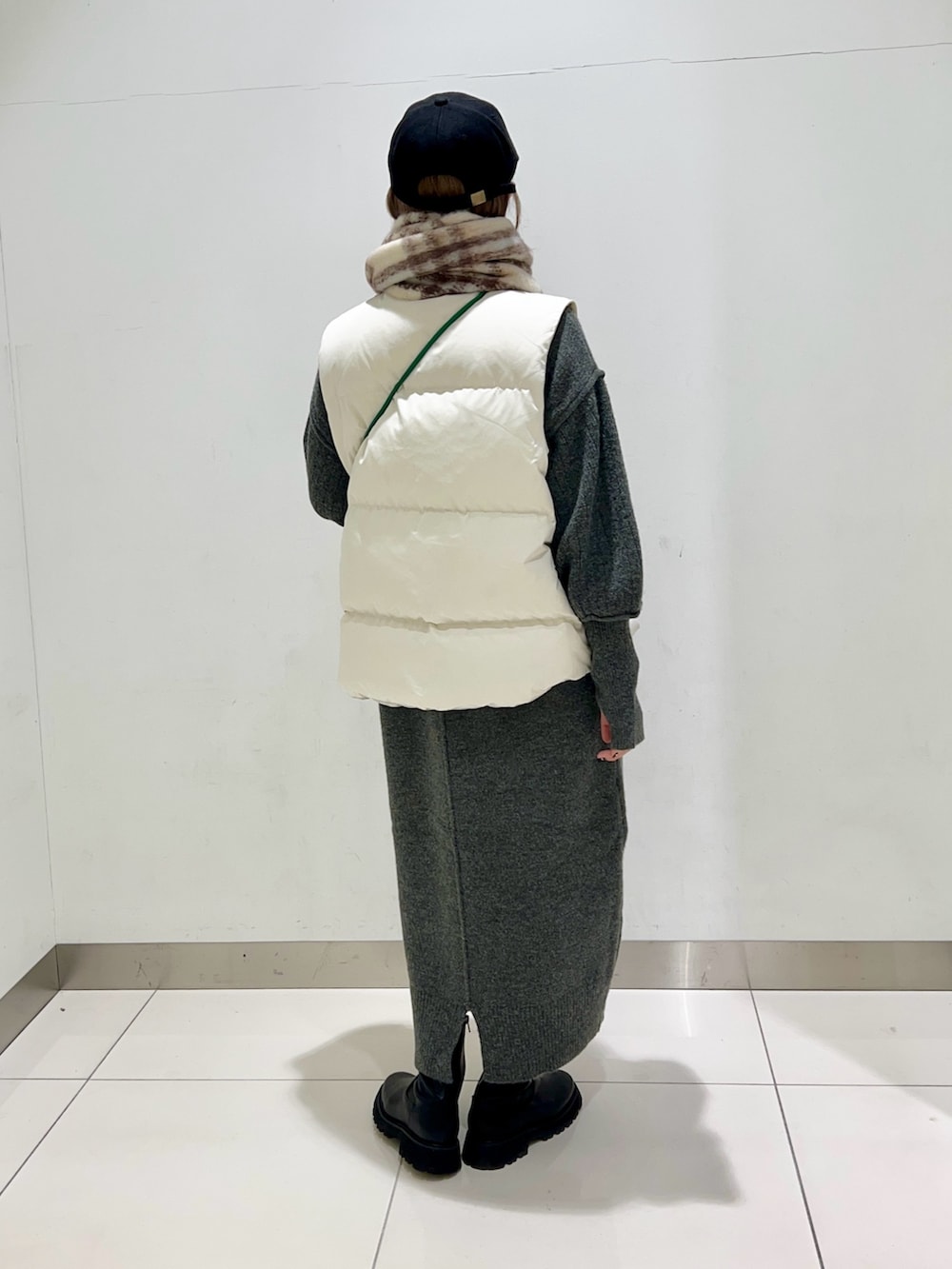 ブラック系のブーツ、グリーン系のショルダーバッグ、ホワイト系のダウンベストを着用したレディースの秋コーディネートの4枚目の写真