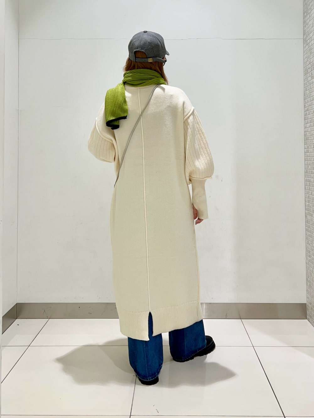 シルバー系のショルダーバッグ、ホワイト系のワンピース、ブルー系のデニムパンツを着用したレディースの冬コーディネートの4枚目の写真