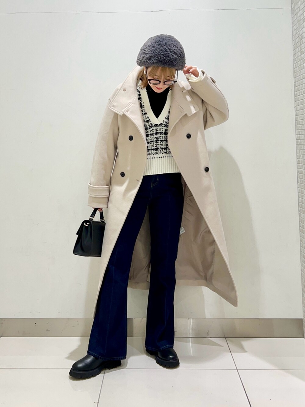 ベージュ系のステンカラーコート、ブルー系のデニムパンツ、ブラック系のショルダーバッグを着用したレディースの冬コーディネートの7枚目の写真