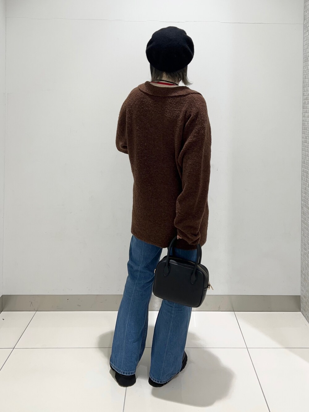 ブラック系のブーツ、ブルー系のデニムパンツ、ブラック系のボストンバッグを着用したレディースの秋コーディネートの4枚目の写真