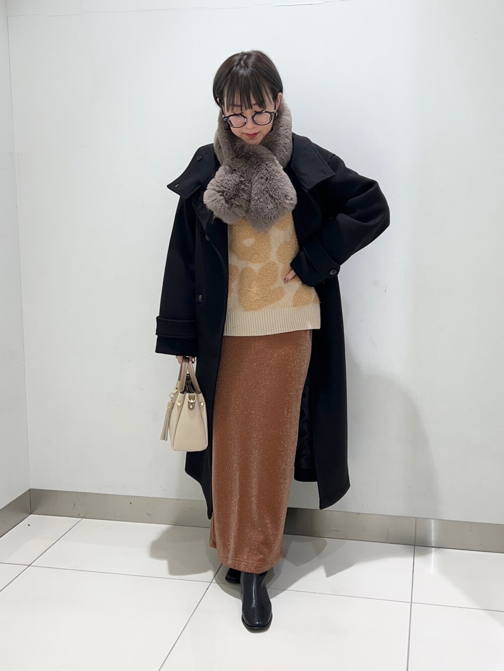 ブラック系のブーツ、ホワイト系のトートバッグ、ブラウン系のスカートを着用したレディースの秋コーディネートの2枚目の写真