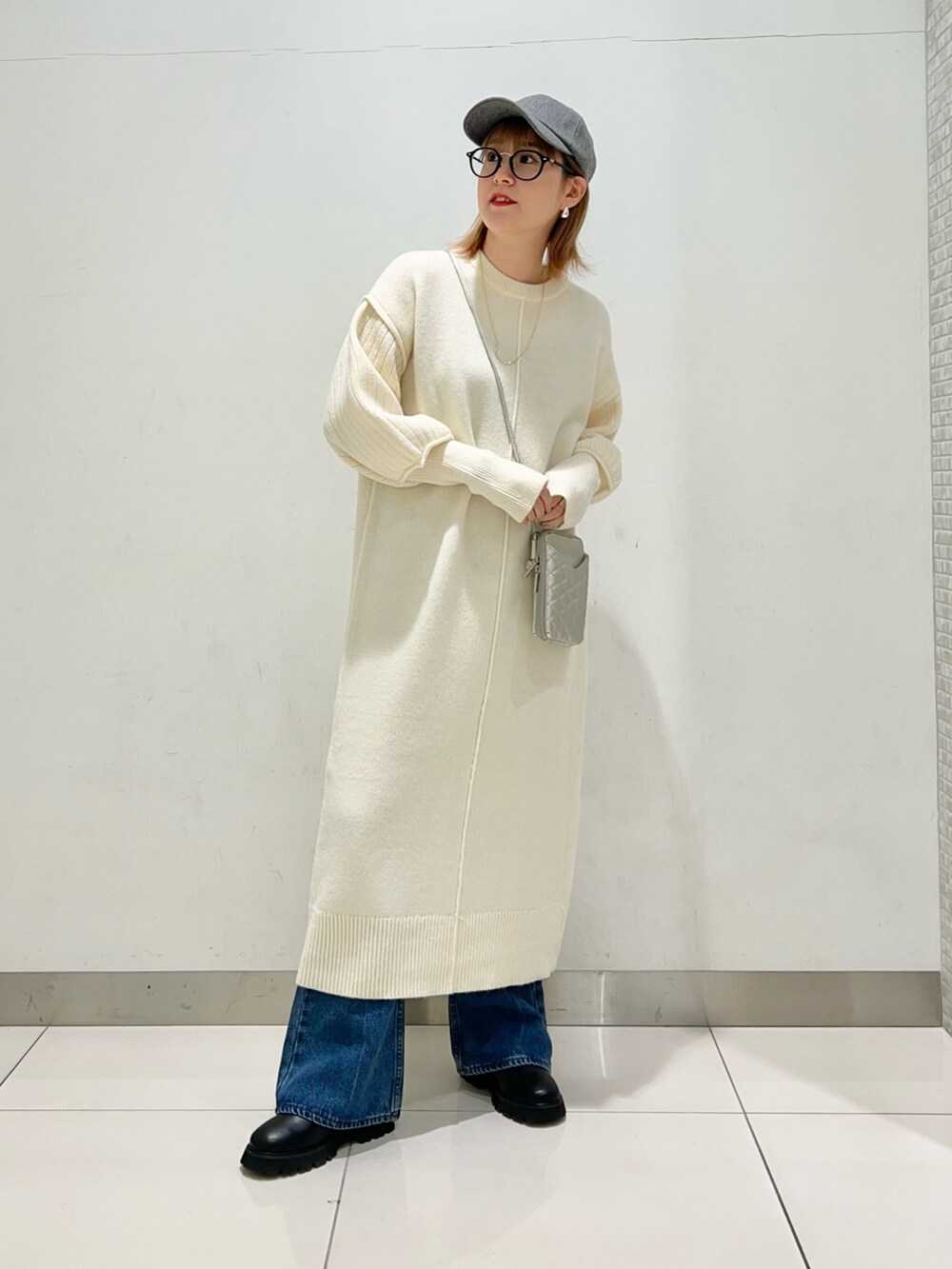 シルバー系のショルダーバッグ、ホワイト系のワンピース、ブルー系のデニムパンツを着用したレディースの冬コーディネートの8枚目の写真