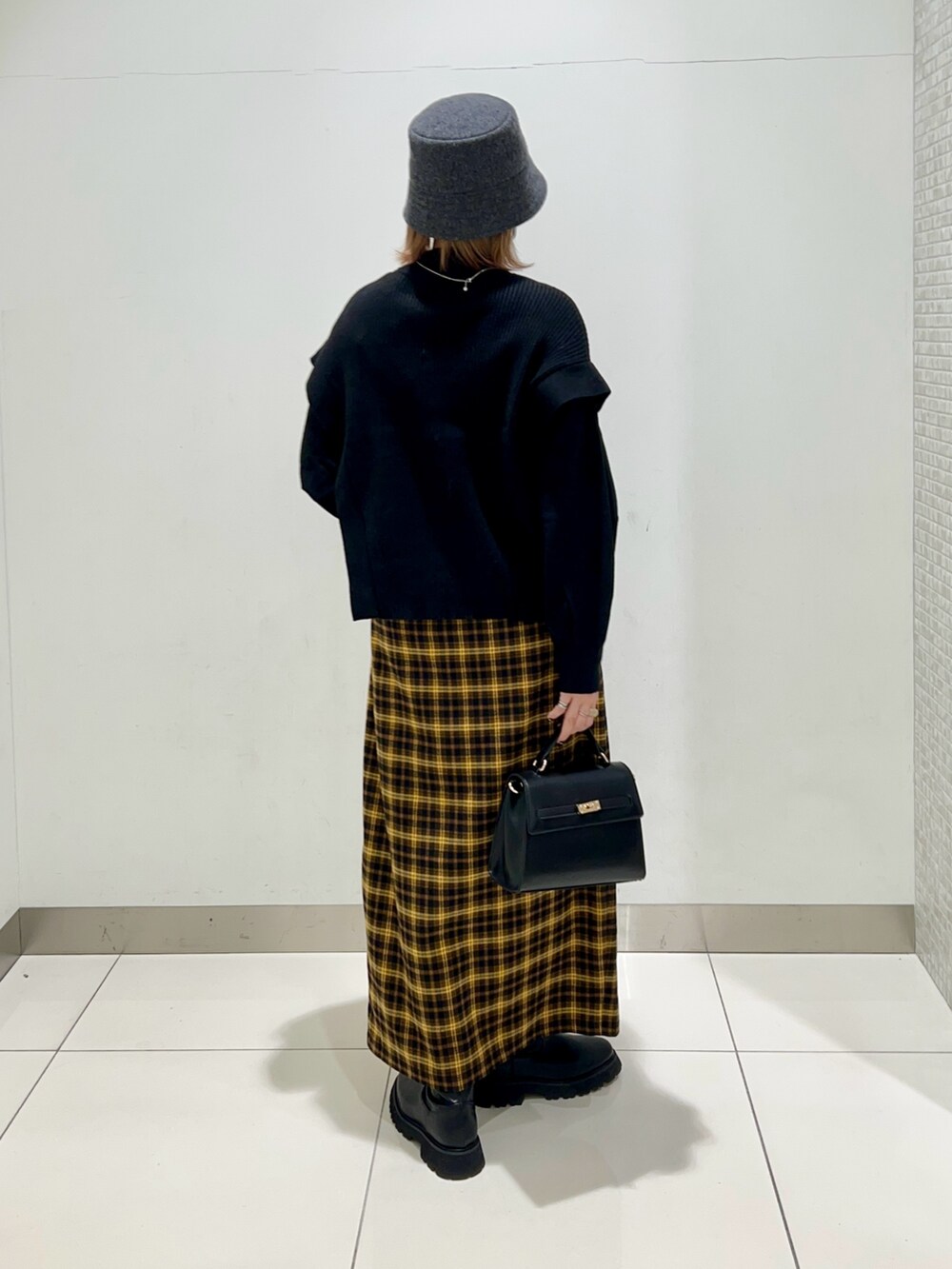 ホワイト系のジャケット/アウター、ブラック系のニット/セーター、イエロー系のスカートを着用したレディースの冬コーディネートの9枚目の写真