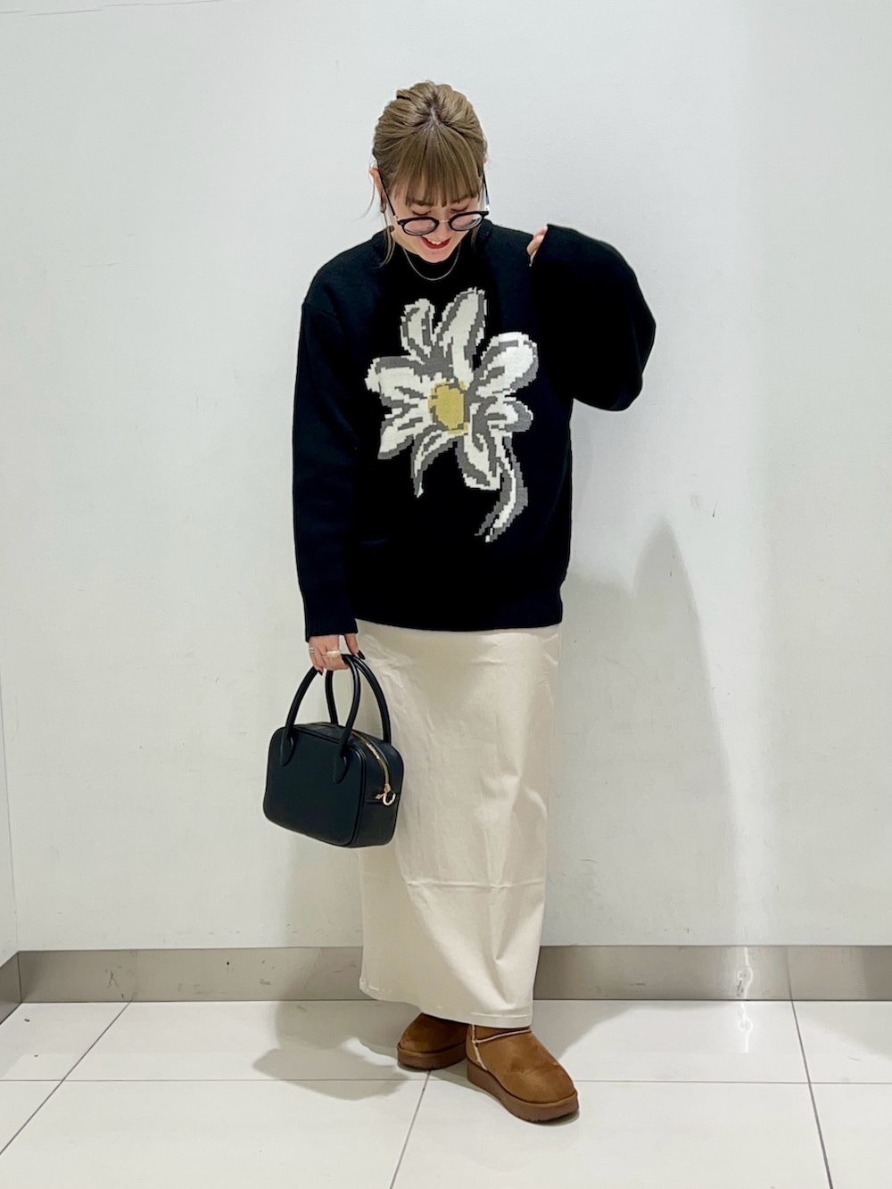 ブラック系のボストンバッグ、ベージュ系のスカート、ブラック系のニット/セーターを着用したレディースの冬コーディネートの8枚目の写真