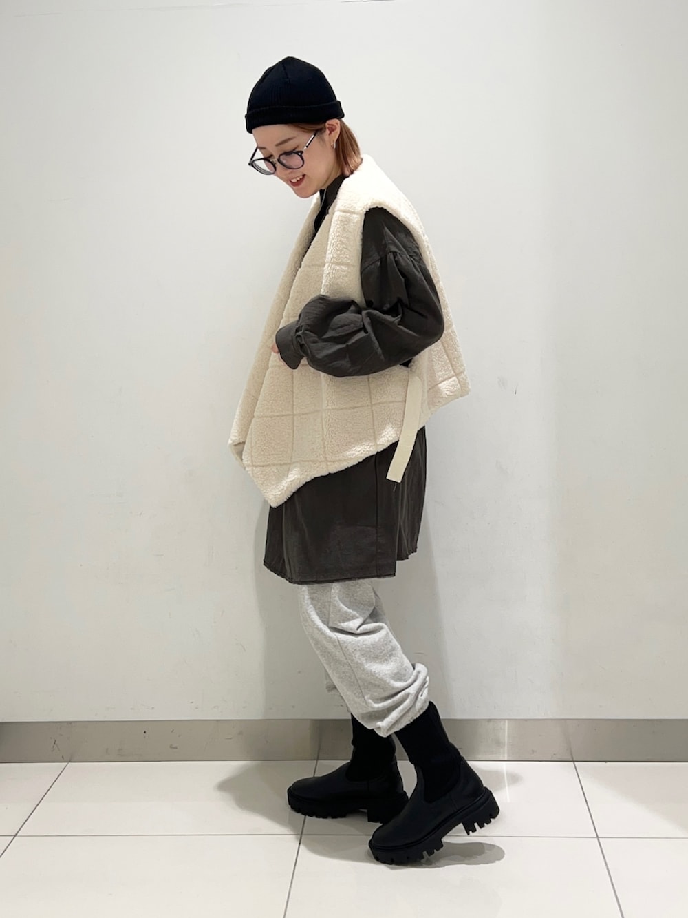 ホワイト系のベスト、グリーン系のワンピース、グレー系のその他パンツを着用したレディースの秋コーディネートの3枚目の写真