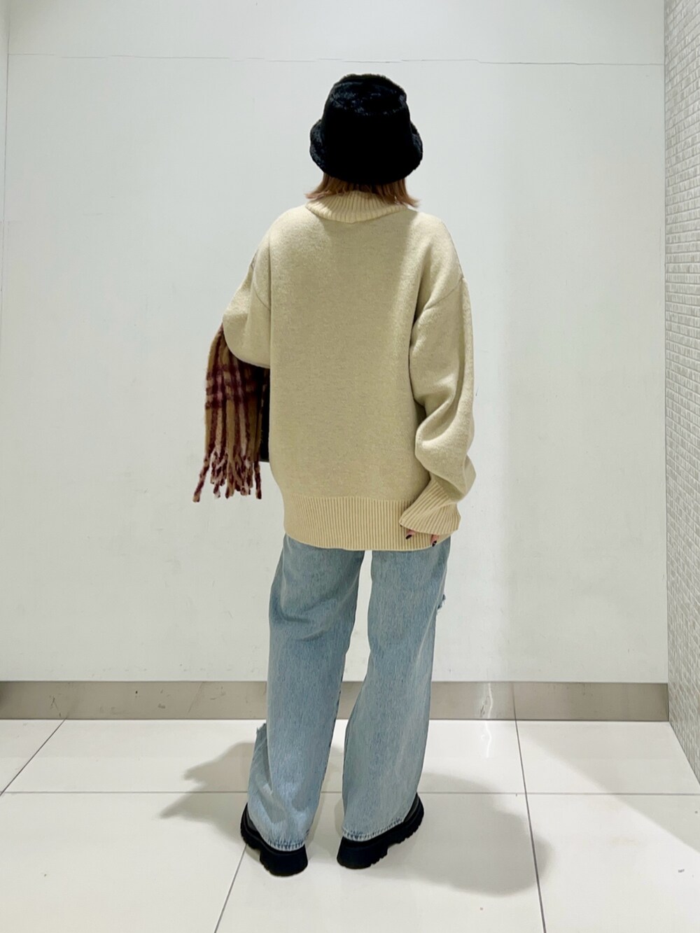 ブラック系のショルダーバッグ、ブルー系のデニムパンツ、ブラック系のブーツを着用したレディースの冬コーディネートの4枚目の写真