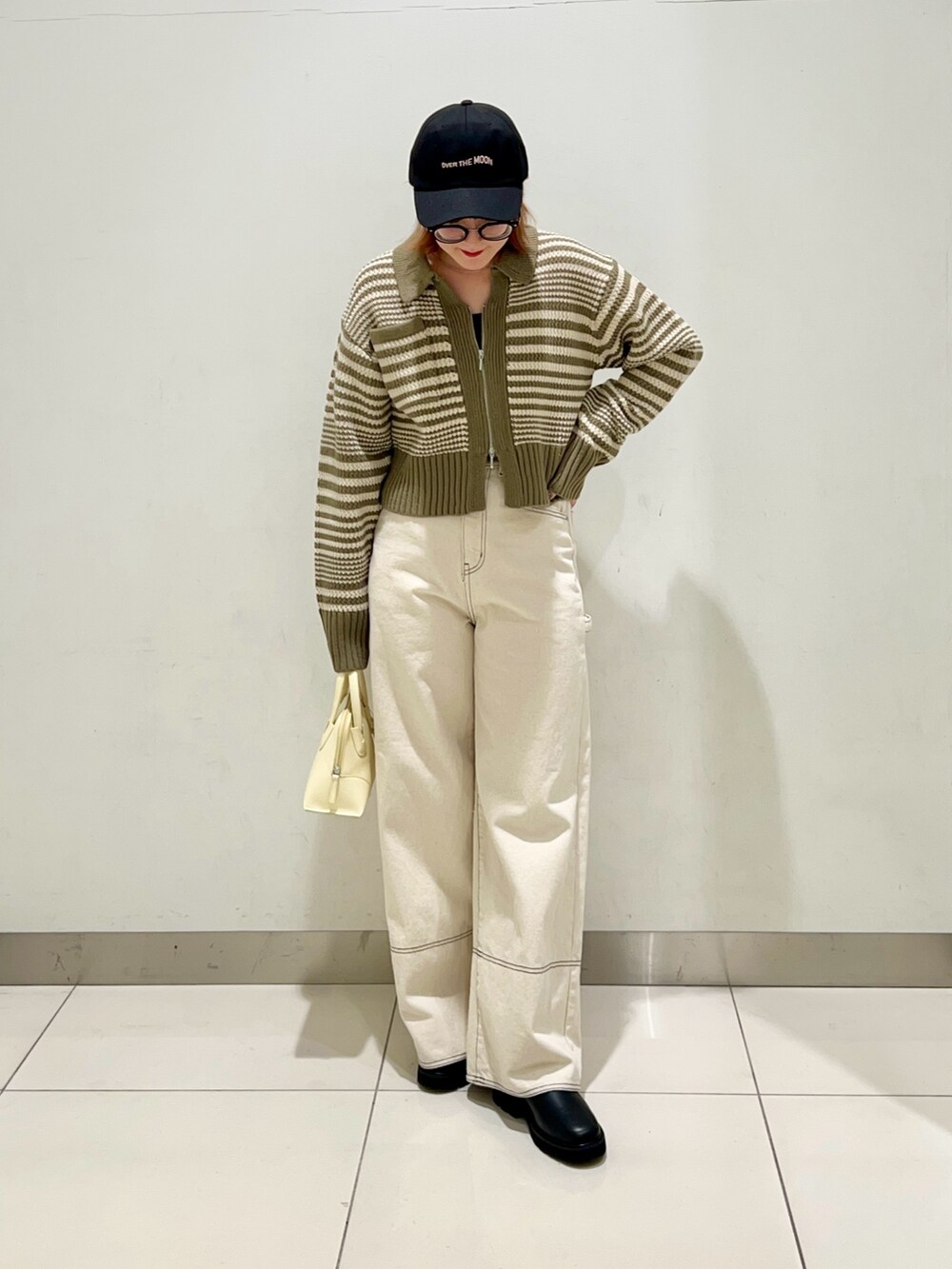 グリーン系のニット/セーター、ホワイト系のデニムパンツ、イエロー系のショルダーバッグを着用したレディースの冬コーディネートの7枚目の写真