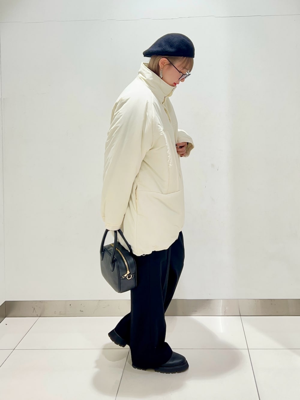 ブラック系のボストンバッグ、ブラック系のスラックス、ブラック系のブーツを着用したレディースの秋コーディネートの5枚目の写真