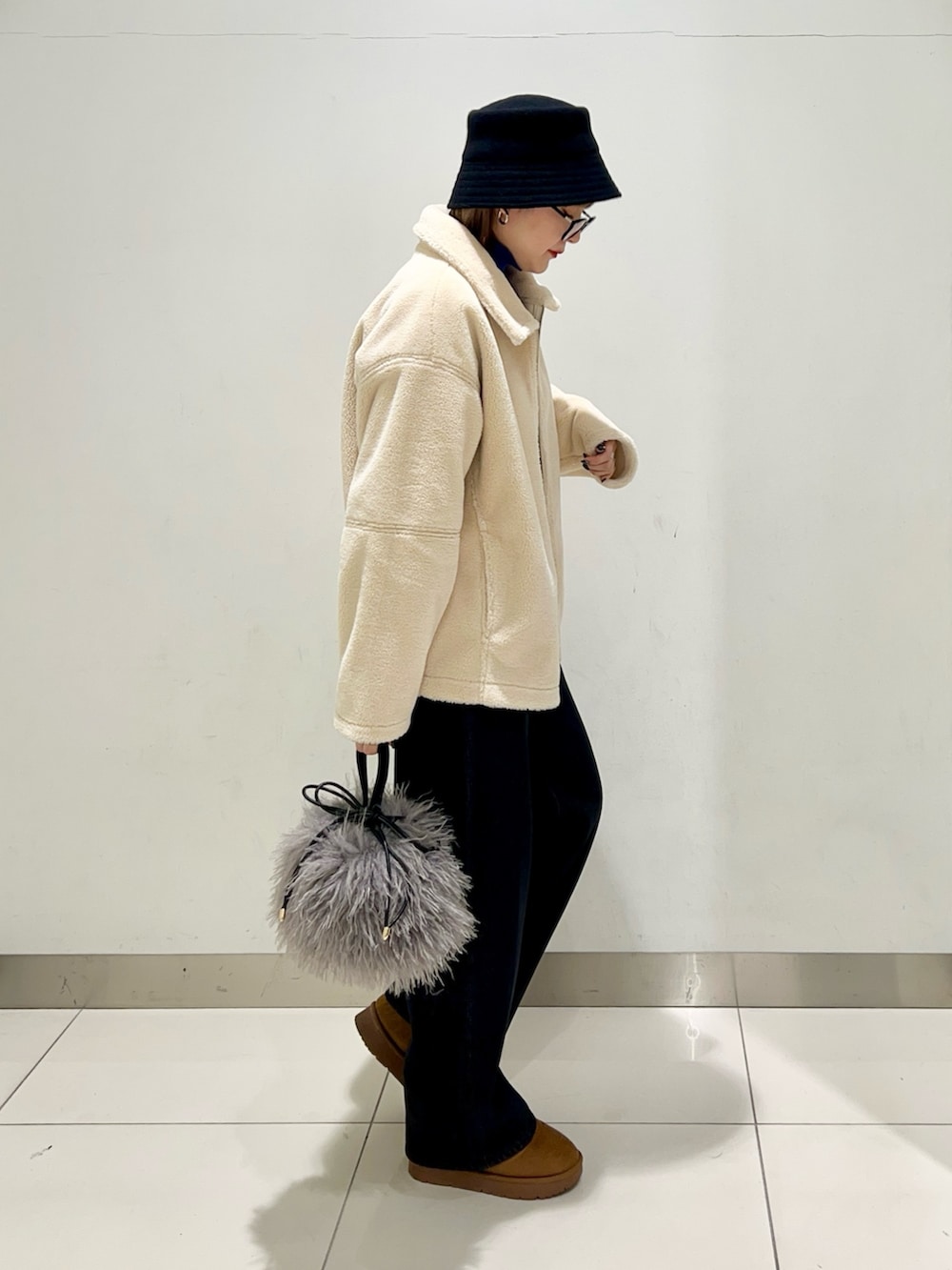 ブラック系のデニムパンツ、ブルー系のニット/セーター、ホワイト系のブルゾンを着用したレディースの冬コーディネートの5枚目の写真