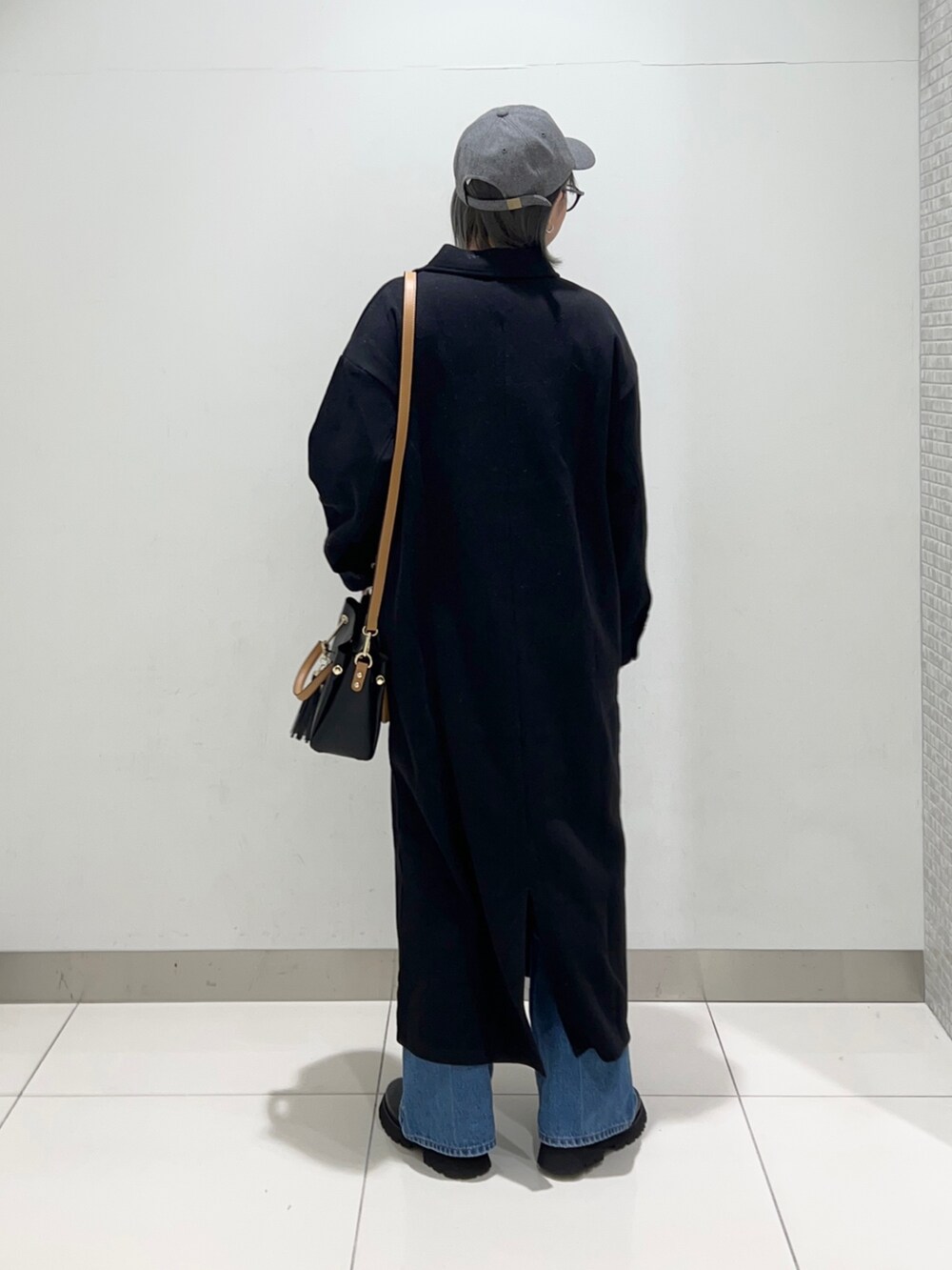 ブラック系のトートバッグ、ブラック系のワンピース、ブラック系のブーツを着用したレディースの秋コーディネートの7枚目の写真