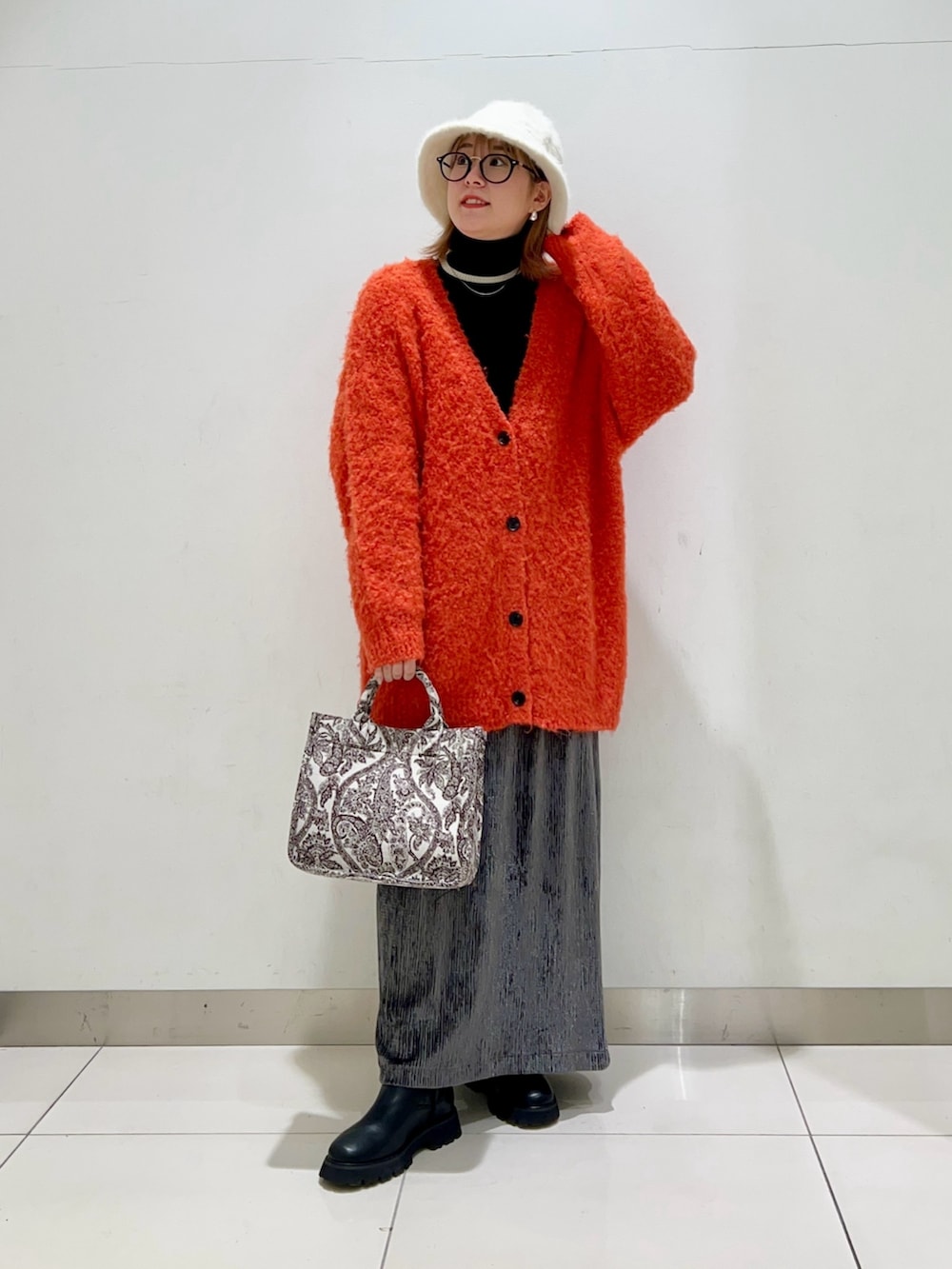 ブラック系のニット/セーター、オレンジ系のカーディガン/ボレロ、ブラウン系のトートバッグを着用したレディースの冬コーディネートの6枚目の写真
