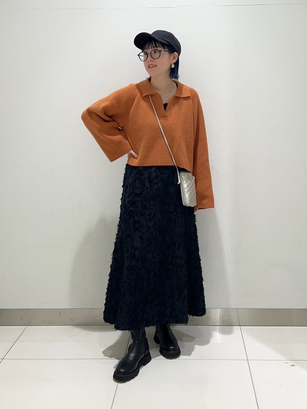 ブラック系のワンピース、オレンジ系のニット/セーター、ブラック系のブーツを着用したレディースの秋コーディネートの2枚目の写真