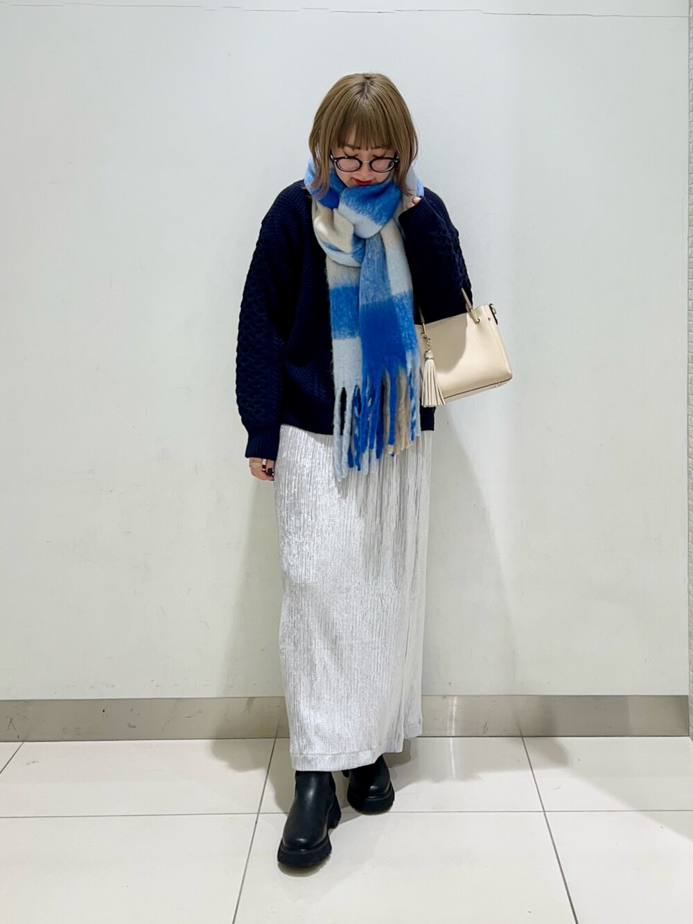 ブラック系のブーツ、グレー系のスカート、ブルー系のニット/セーターを着用したレディースの冬コーディネートの2枚目の写真