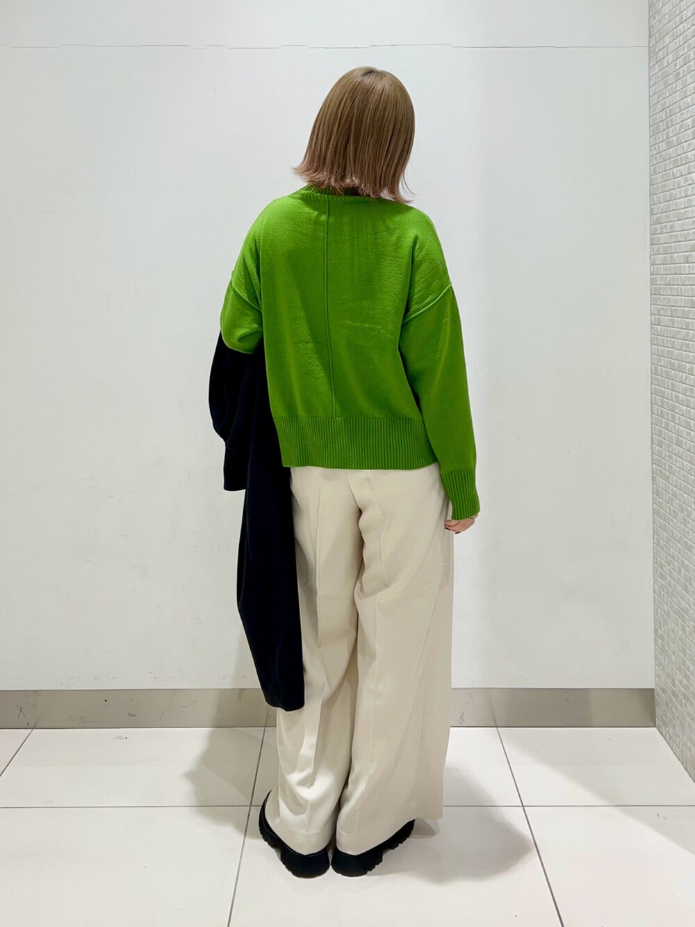 グリーン系のニット/セーター、ホワイト系のその他パンツ、ブラック系のブーツを着用したレディースの冬コーディネートの3枚目の写真