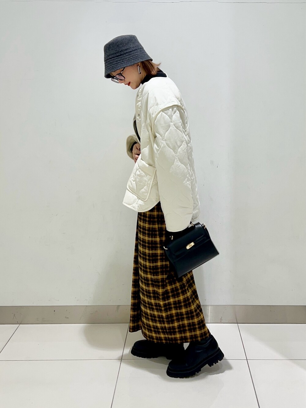 ホワイト系のジャケット/アウター、ブラック系のニット/セーター、イエロー系のスカートを着用したレディースの冬コーディネートの3枚目の写真