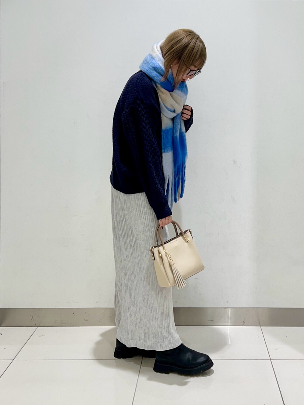 ブラック系のブーツ、グレー系のスカート、ブルー系のニット/セーターを着用したレディースの冬コーディネートの5枚目の写真