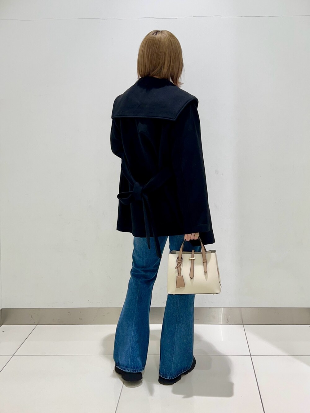 ブラック系のブーツ、ホワイト系のハンドバッグ、ブラック系のその他アウターを着用したレディースの冬コーディネートの4枚目の写真