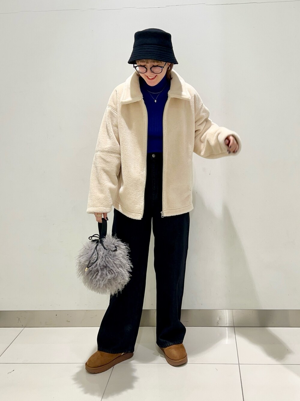 ブラック系のデニムパンツ、ブルー系のニット/セーター、ホワイト系のブルゾンを着用したレディースの冬コーディネートの2枚目の写真