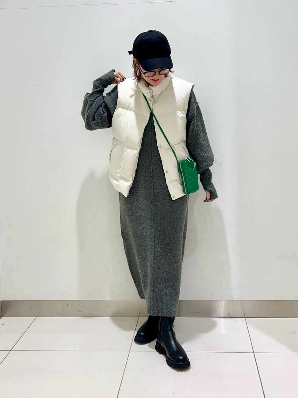 ブラック系のブーツ、グリーン系のショルダーバッグ、ホワイト系のダウンベストを着用したレディースの秋コーディネートの9枚目の写真