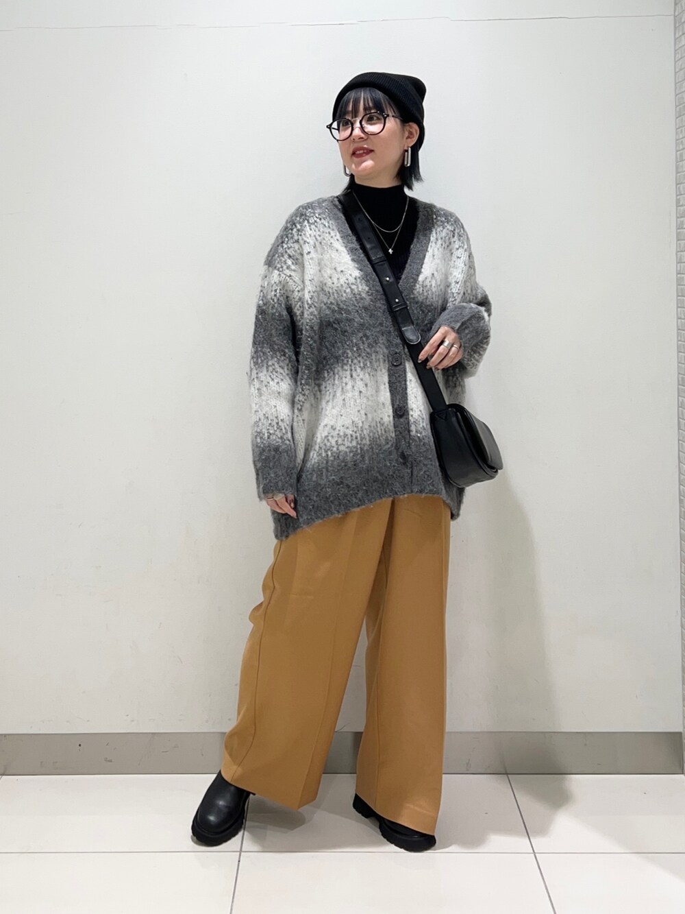 ブラック系のニット/セーター、ブラック系のショルダーバッグ、グレー系のカーディガン/ボレロを着用したレディースの秋コーディネートの2枚目の写真