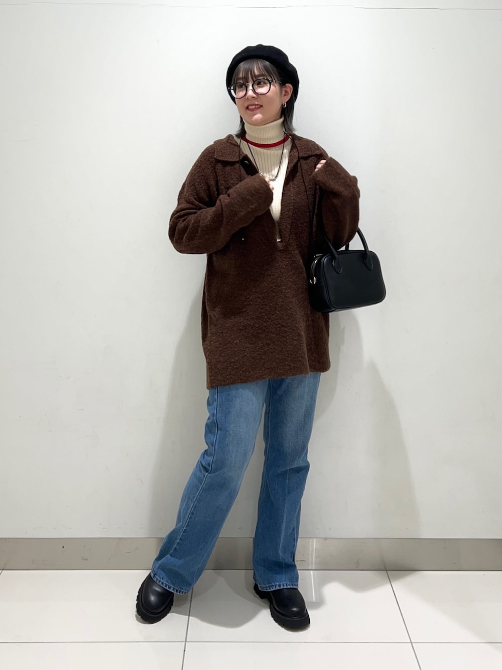 ブラック系のブーツ、ブルー系のデニムパンツ、ブラック系のボストンバッグを着用したレディースの秋コーディネートの7枚目の写真