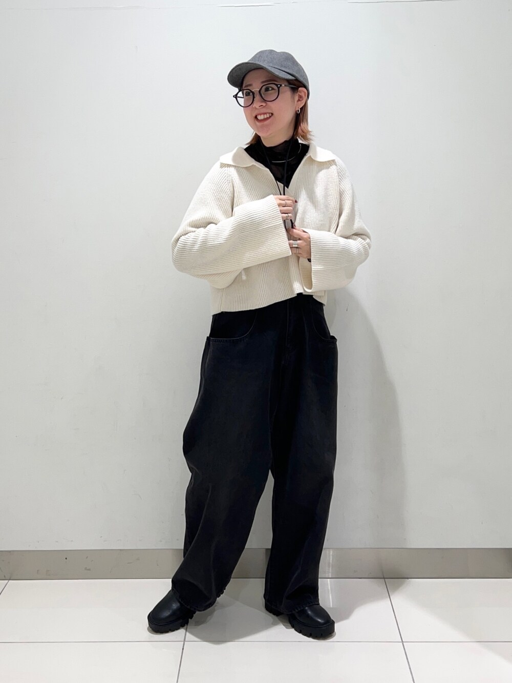 ブラック系のデニムパンツ、ブラック系のブーツ、ホワイト系のニット/セーターを着用したレディースの秋コーディネートの6枚目の写真