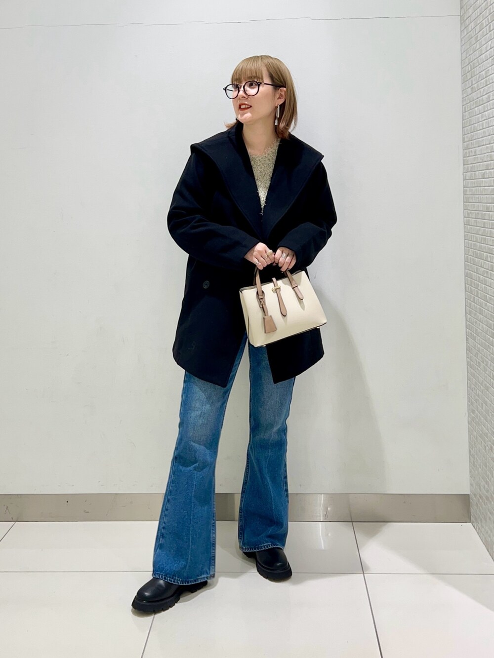 ブラック系のブーツ、ホワイト系のハンドバッグ、ブラック系のその他アウターを着用したレディースの冬コーディネートの6枚目の写真