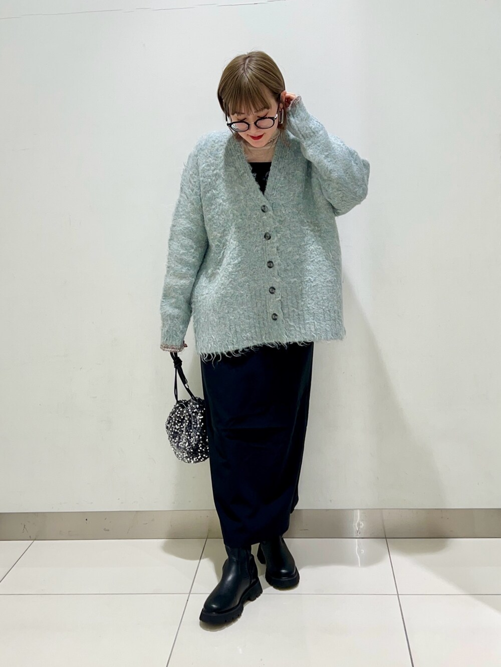 ブルー系のカーディガン/ボレロ、ブラック系のワンピース、ブラック系のブーツを着用したレディースの秋コーディネートの2枚目の写真