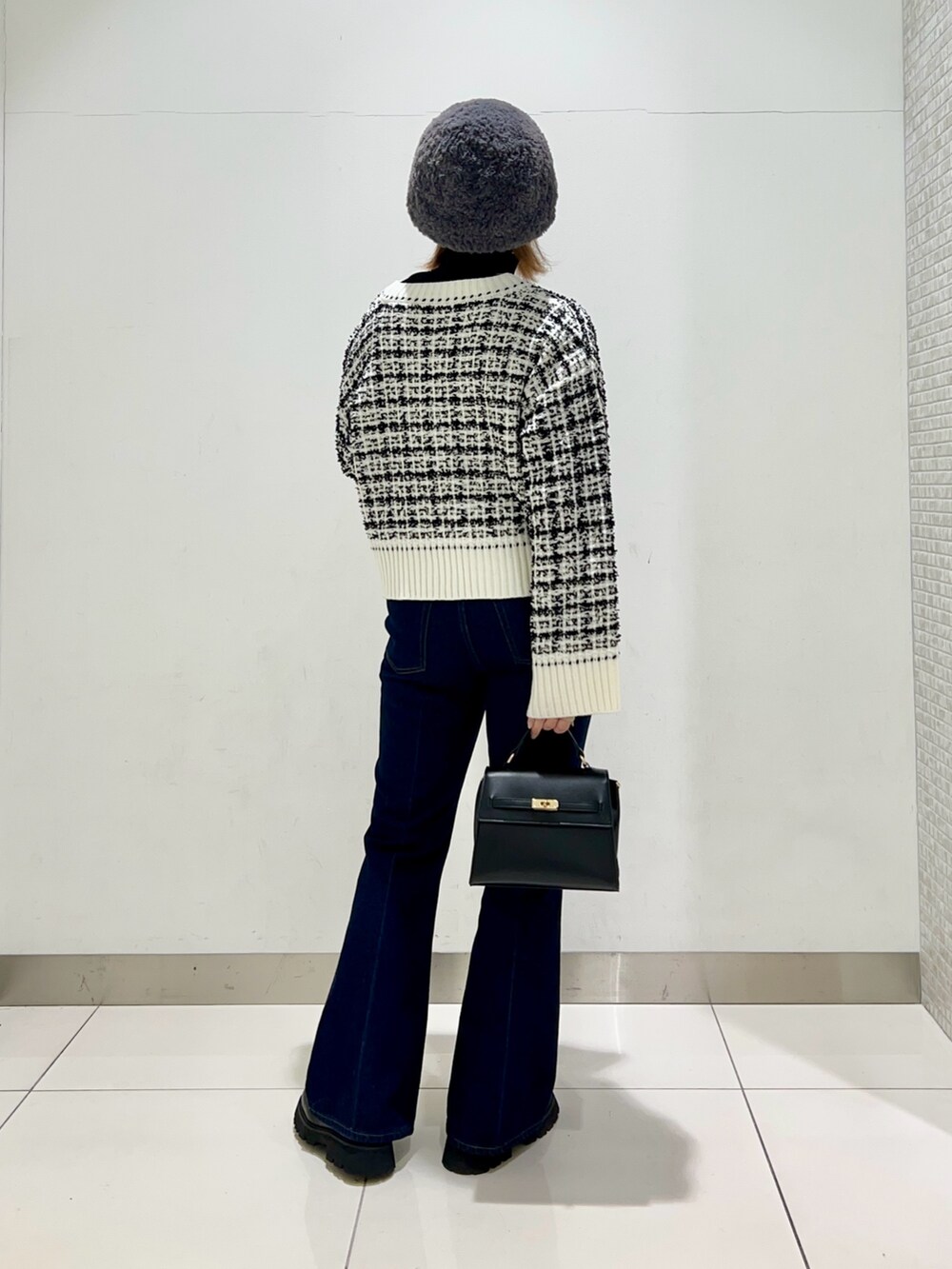 ベージュ系のステンカラーコート、ブルー系のデニムパンツ、ブラック系のショルダーバッグを着用したレディースの冬コーディネートの9枚目の写真