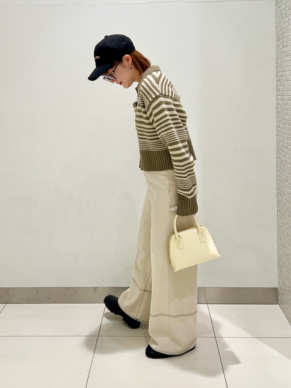 グリーン系のニット/セーター、ホワイト系のデニムパンツ、イエロー系のショルダーバッグを着用したレディースの冬コーディネートの3枚目の写真
