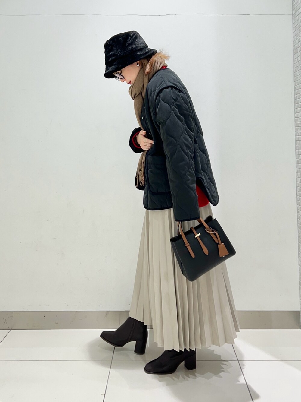 ブラウン系のブーツ、ベージュ系のスカート、ブラック系のハンドバッグを着用したレディースの冬コーディネートの5枚目の写真