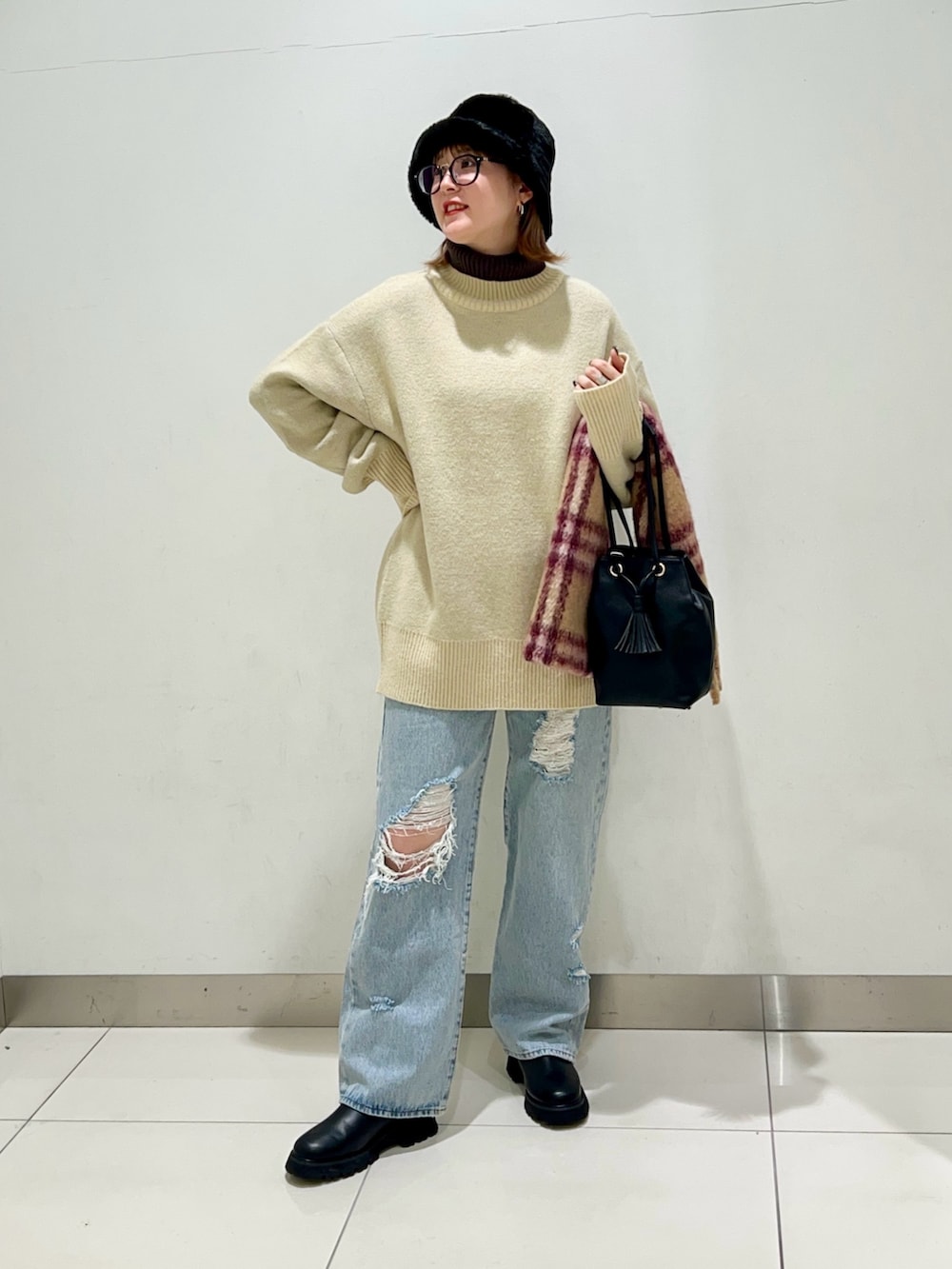 ブラック系のショルダーバッグ、ブルー系のデニムパンツ、ブラック系のブーツを着用したレディースの冬コーディネートの2枚目の写真