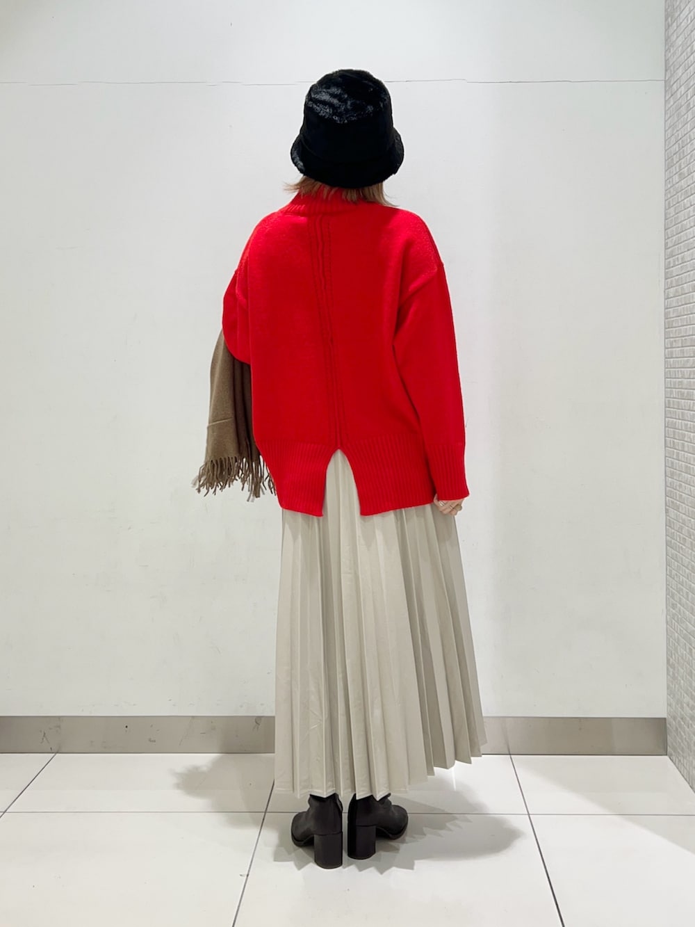 ブラウン系のブーツ、ベージュ系のスカート、ブラック系のハンドバッグを着用したレディースの冬コーディネートの3枚目の写真