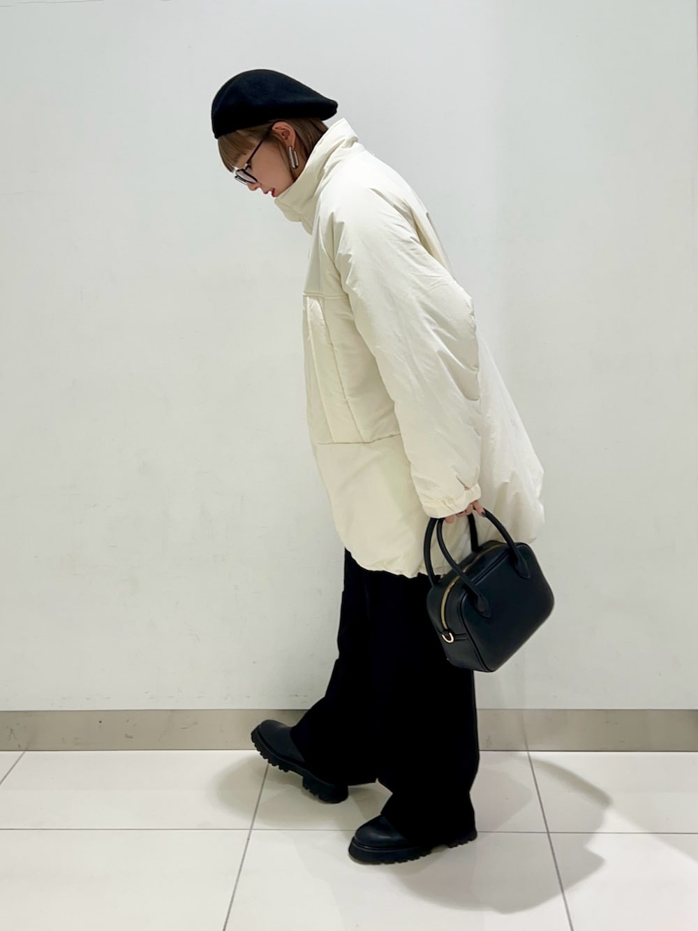 ブラック系のボストンバッグ、ブラック系のスラックス、ブラック系のブーツを着用したレディースの秋コーディネートの3枚目の写真